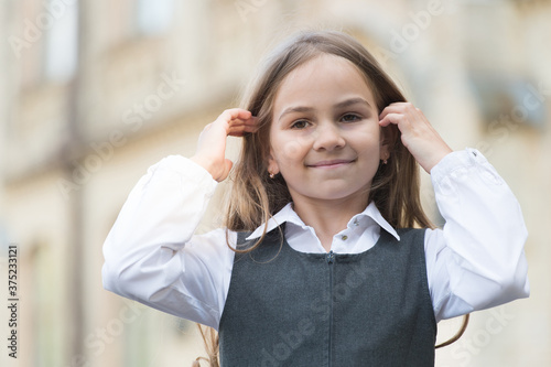 Happy kid in fashion uniform with back to school look fix long hair outdoors, beauty