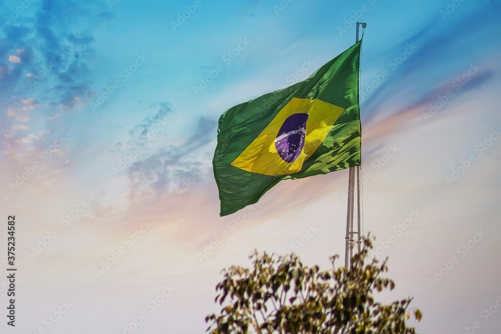 Bandeira do Brasil balançando ao vento com céu ao fundo. - obrazy, fototapety, plakaty 
