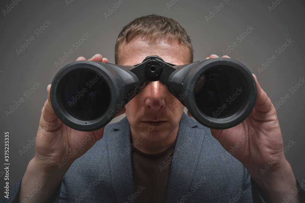 Serious man is looking through a binoculars in hands close up. Serious man is looking through a binoculars in hands close up.
