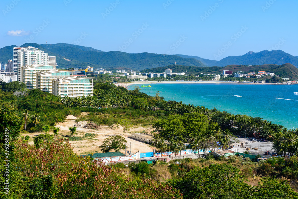 View from the hotel to clear turquoise sea, mountains, beach, jet skis, motor boats and parachutes on the coast of Dadonghai Bay in South China Sea. Sunny day