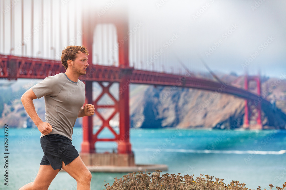 Man runner running by the Golden Gate Bridge in San Francisco, USA. Sports male athlete jogging training outdoors in autumn by scenic landscape.