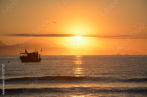 sol nascente, barco, paisagem laranja, relexo na água © dririchetto