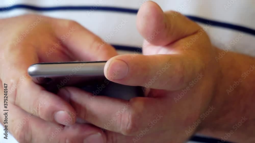 Closeup of male hands typing an sms message via smartphone Closeup of male hands typing an sms message via smartphone