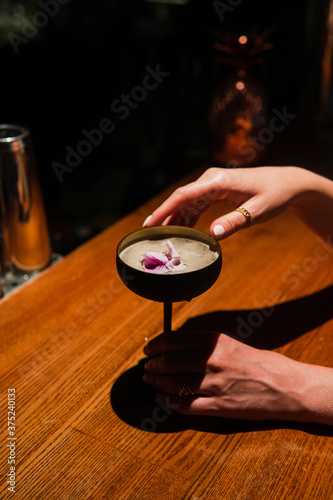 Alcohol cocktail with female hands on the dark background