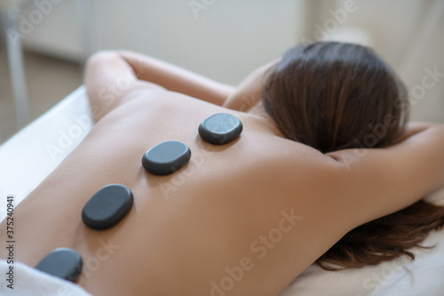 Dark-haired woman lying on the couch and having hot stone therapy