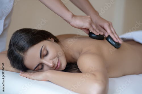 Massage therapist doing stone massage to a female customer