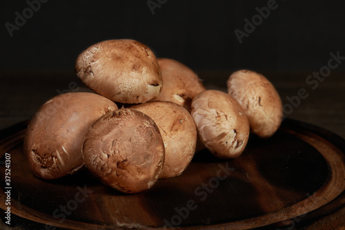 Fresh brown champignon mushrooms on wooden table.