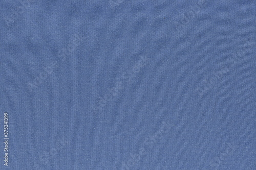 The texture of a knitted dense fabric of blue denim color. Abstract fabric background in a pleasant blue color.