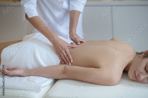 Massage therapist gently massaging young womans lower back