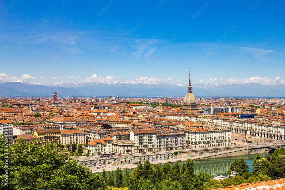 Aerial PAnoramic summer view on Turin skyline, with the city center, Po river, Mole Antonelliana, modern skyscrapers and other landmark seen from viewpoint the Monte dei Cappuccini on snowy alps Italy