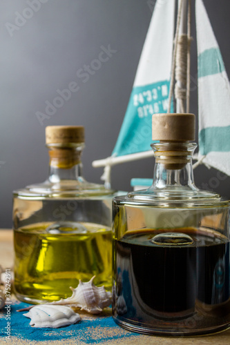 Essig und Öl in schönen Flaschen mit grauem Hintergrund und Segelboot