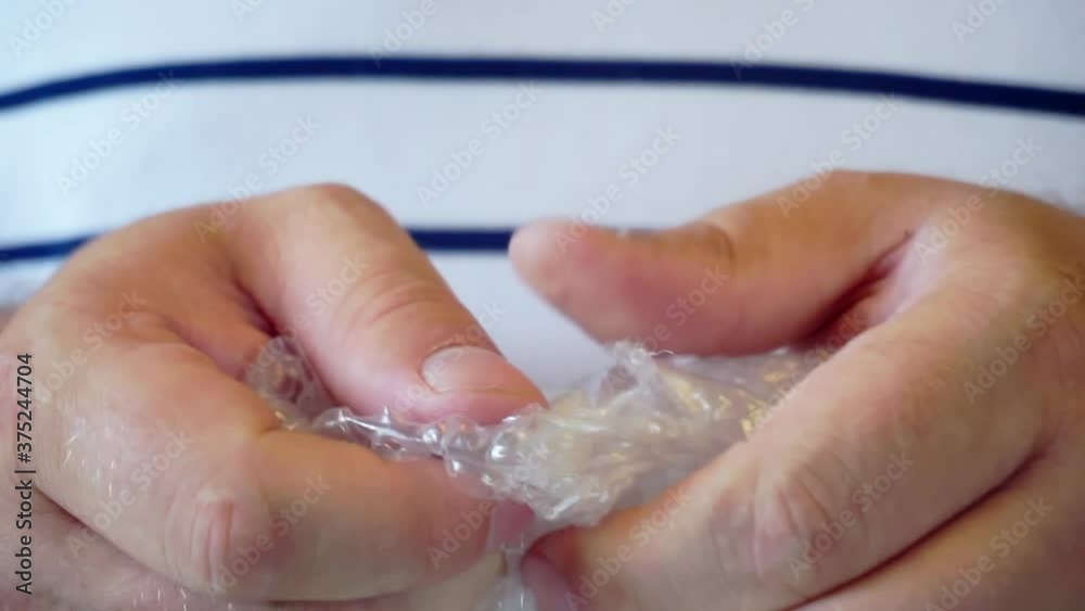 hands tearing the packaging film with bubbles to calm down. hands tearing the packaging film with bubbles to calm down.