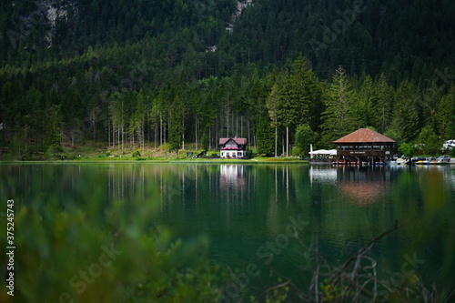 Perfect reflection of a typical Tyrolean house in the woods over Dobbiaco Lake