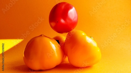 four yellow and red pepper on an orange background. harvest time. Levitating peppers