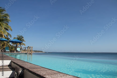 Fototapeta Naklejka Na Ścianę i Meble -  Beautiful beach resort bar at the Indian Ocean, amazing seascape with turquoise colors, palm trees and infinity pool, Mozambique, Pemba city