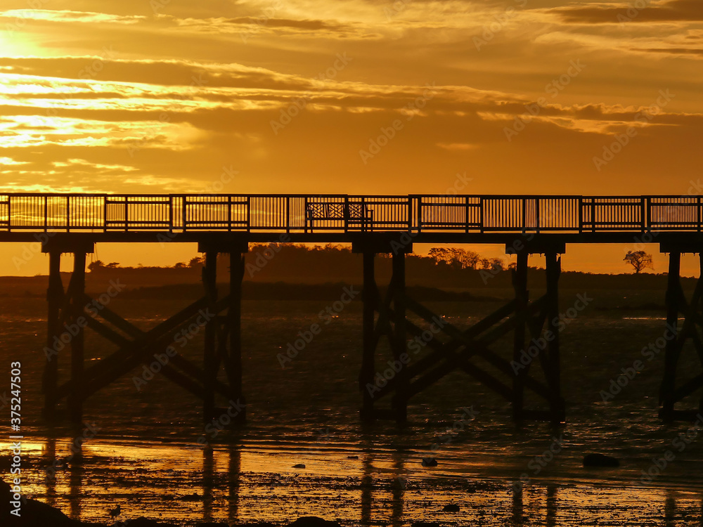 Obraz premium Fishing pier silhouette with sunris yellow colored sky