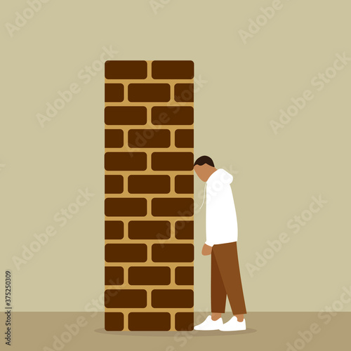 Male character rests his head against a brick wall