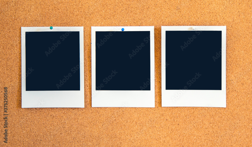 Fototapeta premium Blank square Instant pictures pinned to a corkboard with bugpin pushpins.