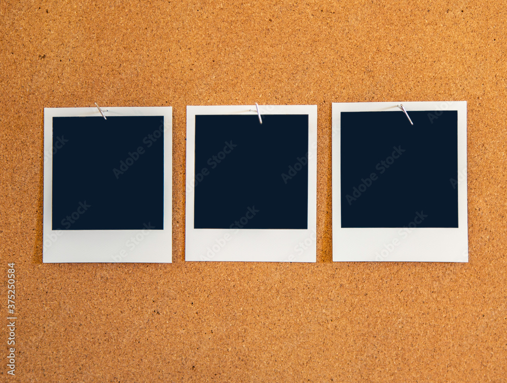 Fototapeta premium Blank square Instant pictures pinned to a corkboard with metal t-pin pushpins.