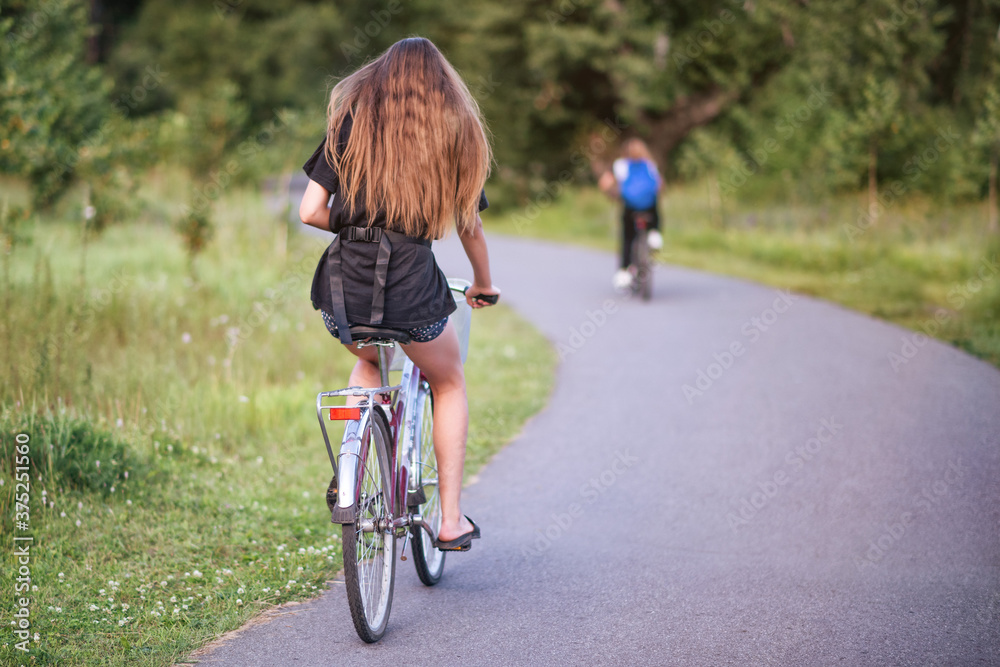 A girl riding a bicycle in a park in summer in the sunny morning. A girl riding a bicycle in a park in summer in the sunny morning.