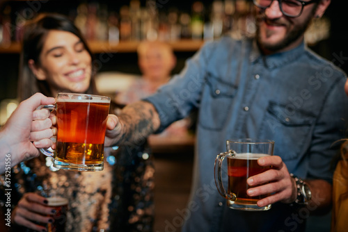 Closeup of man passing beer to his friend while standing in a pub.