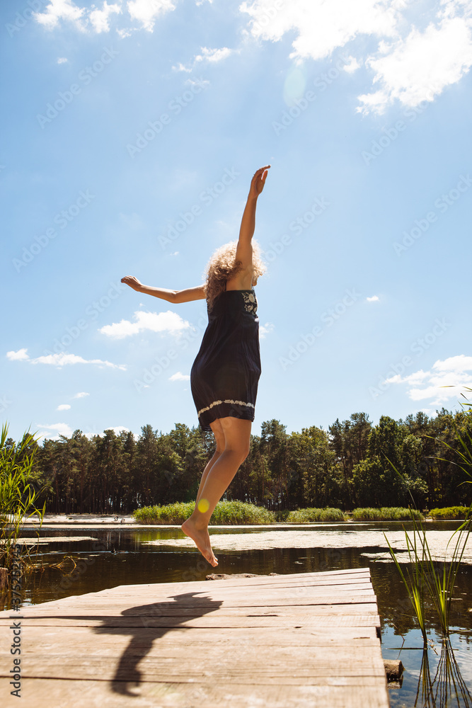 Beautiful girl jump into the water from bridge in summer Beautiful girl jump into the water from bridge in summer