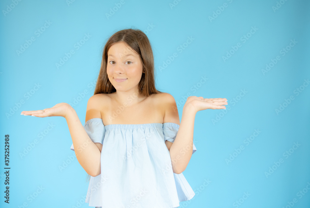 Smiling girl with doubtful gesture on blue background Smiling girl with doubtful gesture on blue background