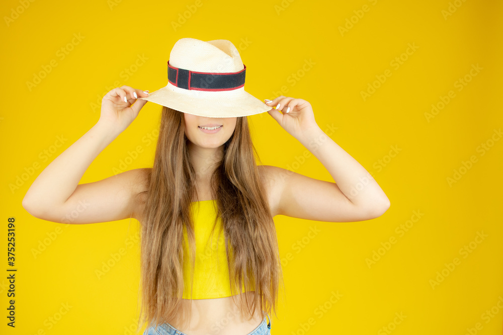 Beautiful girl posing with straw hat on yellow background Beautiful girl posing with straw hat on yellow background