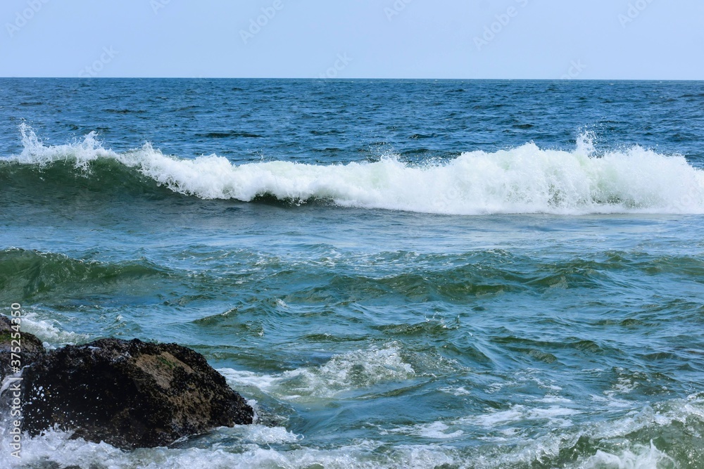 Blue Ocean Waves Crashing Over The Rocks And Shore