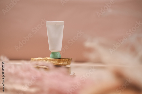 White cosmetic tube on light pink background. Natural minimalism, clean concept. Minimal styling, still life. Beauty blogging, skin care