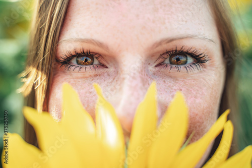 Картината върху платно Close up portrait of Caucasian young woman hiding her face with yellow sunflower