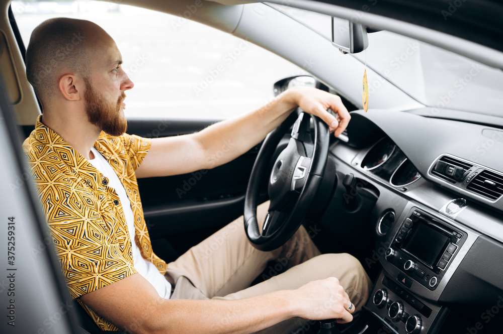 Concentrated bearded man driving his favorite comfortable car, he looks on the road Concentrated bearded man driving his favorite comfortable car, he looks on the road