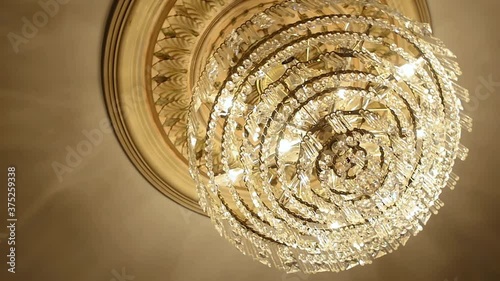 Canada - July 13, 2018: Elegant chandelier with hanging crystal balls and illuminated bulbs looking beautiful on pattern ceiling in a luxurious hall