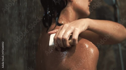 A woman taking shower. Close up view in shower cabin under splashing water