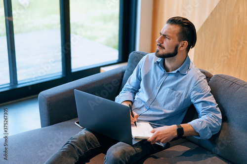 Side view of exhausted business man searching for solution using laptop photo