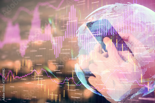 Double exposure of man's hands holding and using a digital device and forex graph drawing. Financial market concept.