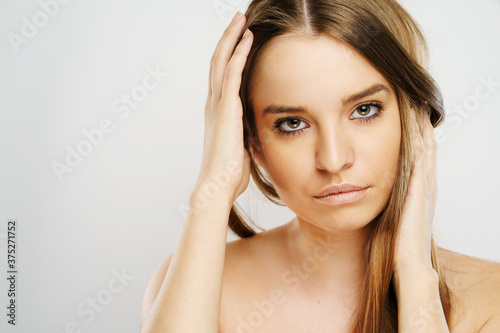 Wallpaper Mural Beauty portrait of beautiful caucasian girl young brunette woman with natural perfect skin and makeup holding hand in hair looking to the camera at studio in front of white background copy space Torontodigital.ca