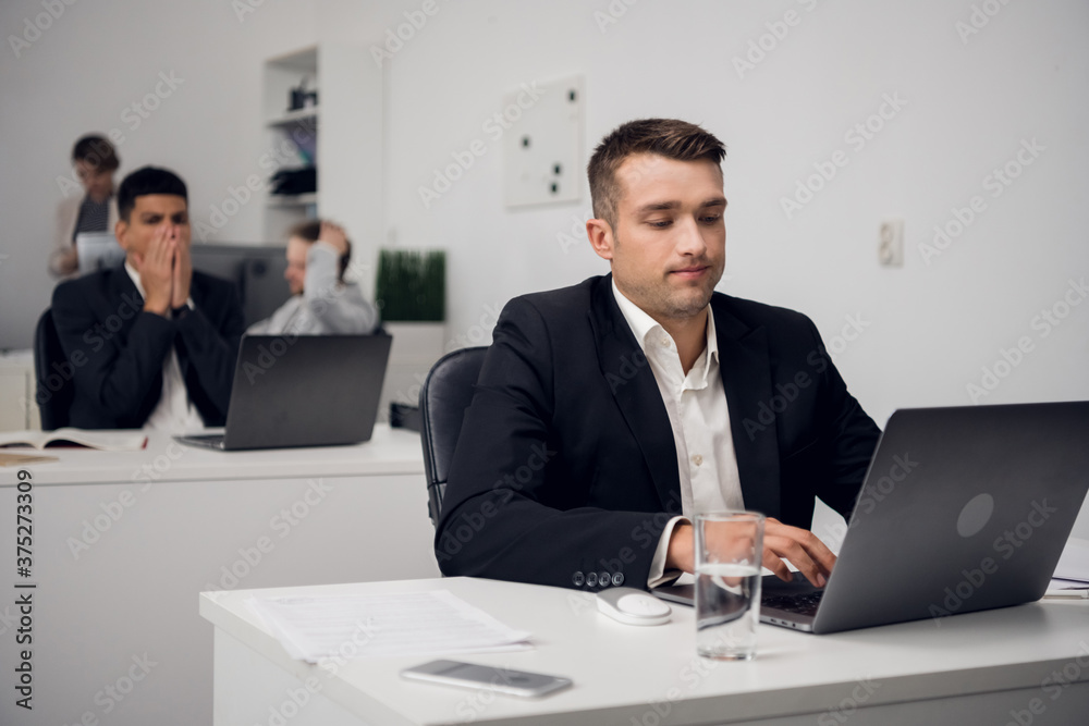 Two managers of a carsharing company are engaged in routine business in the office in a laptop. They are distracted from their work. Two managers of a carsharing company are engaged in routine business in the office in a laptop. They are distracted from their work.