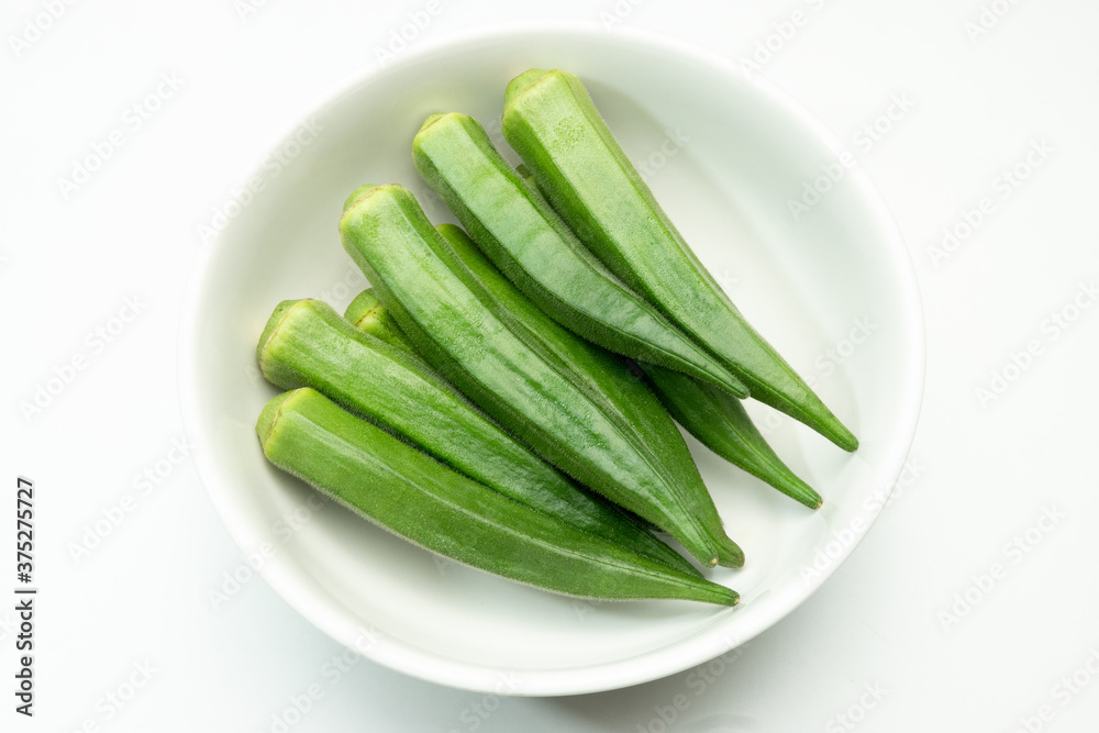 Okra in a white ceramic bowl. (White background.) Okra in a white ceramic bowl. (White background.)