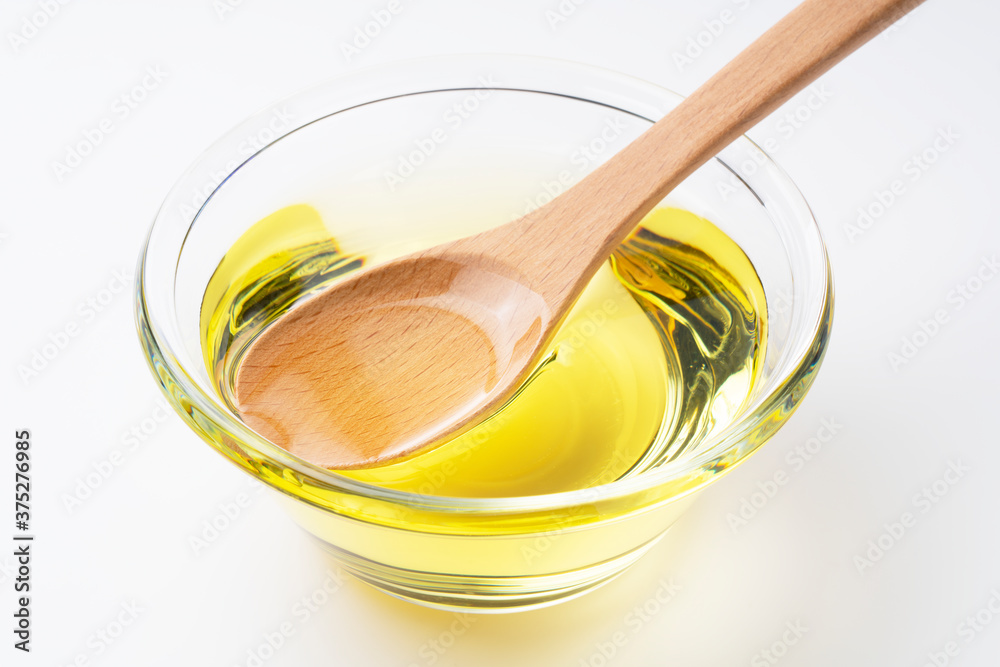 Vegetable oil and wooden spoon on a white background Vegetable oil and wooden spoon on a white background