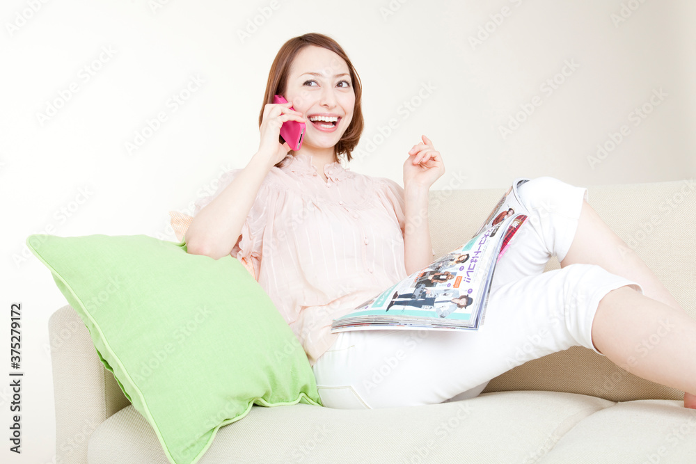 ソファに座って電話する女性 ソファに座って電話する女性