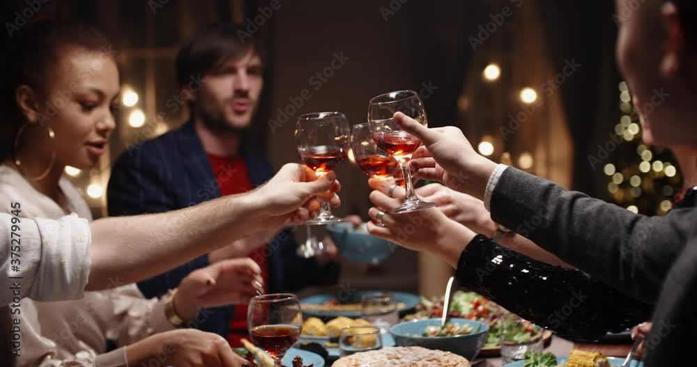 Happy friends celebrating christmas or graduation together, having a dinner party, clinking thir glasses with wine, talking and smiling - celebration, real people 4k footage Happy friends celebrating christmas or graduation together, having a dinner party, clinking thir glasses with wine, talking and smiling - celebration, real people 4k footage