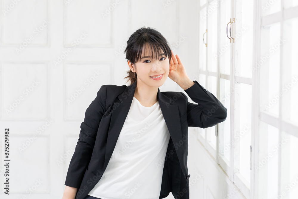 聞き耳をたてる若いビジネスウーマン 聞き耳をたてる若いビジネスウーマン