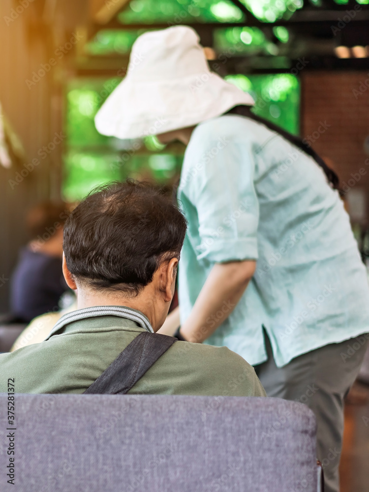 Back view of Asian male customer sit in waiting social distance queue for take away drink in coffee shop. New normal lifestyle concept. Back view of Asian male customer sit in waiting social distance queue for take away drink in coffee shop. New normal lifestyle concept.
