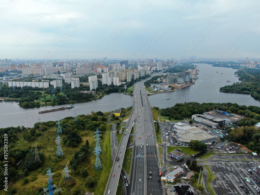 Fototapeta premium Aerial view car traffic on the bridge over the river expressway in the big city. Beautiful landscape of the city from the drone