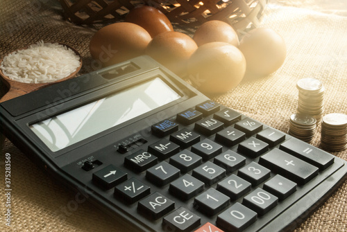 Calculator. Coins. Eggs and rice in a wooden spoon on a sackcloth. photo