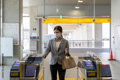 マスク姿でエスカレーターに通勤で乗る女性