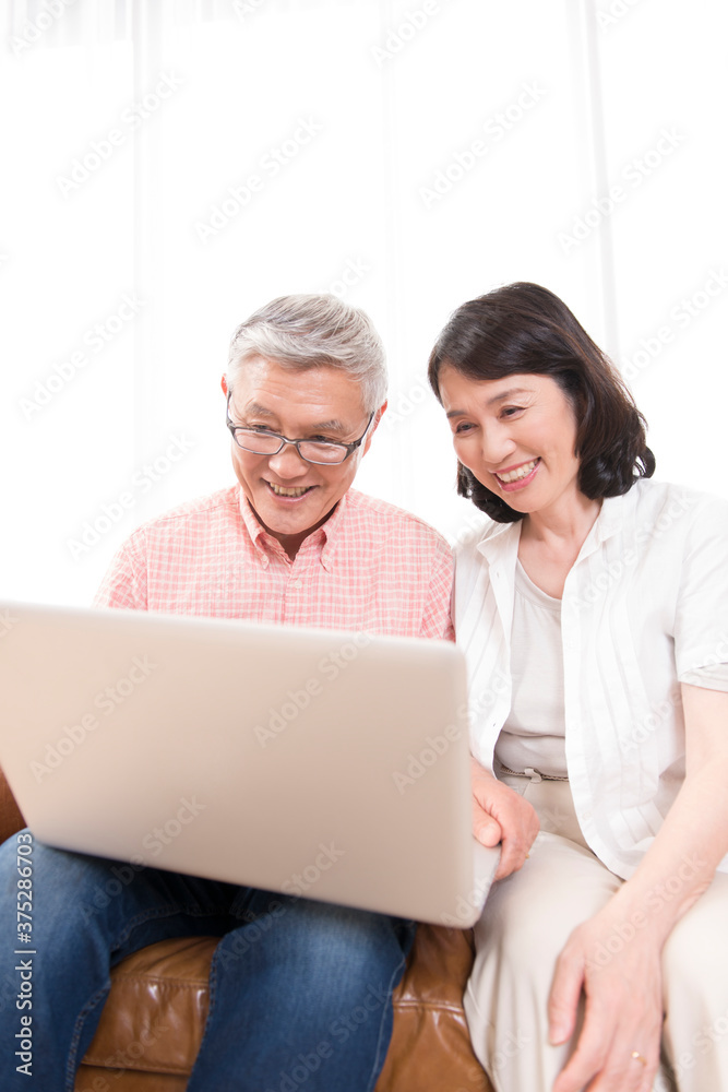 ノートパソコンを見るシニア夫婦