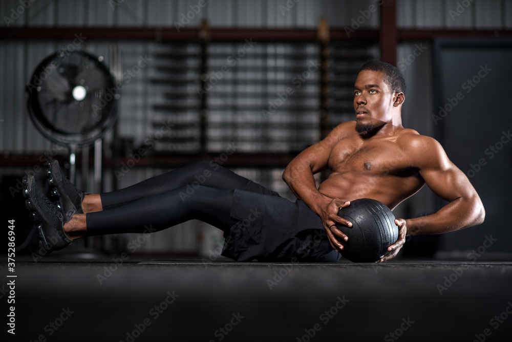 young man with abs in gym with medicine ball young man with abs in gym with medicine ball