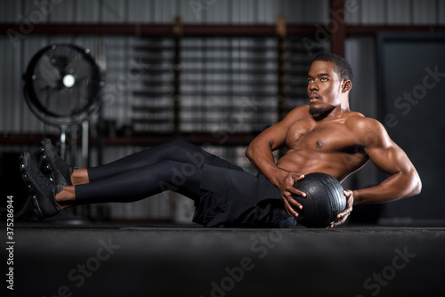 young man with abs in gym with medicine ball 